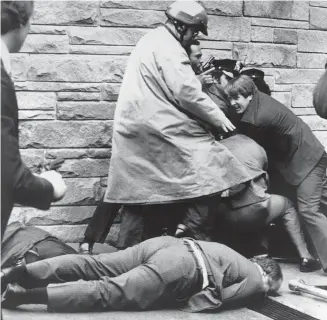  ??  ?? In this March 30, 1981, photo, secret service agents and police wrestle John Hinckley Jr. to the ground as White House press secretary James Brady lies wounded on the sidewalk outside the Washington Hilton after an assassinat­ion attempt on President...