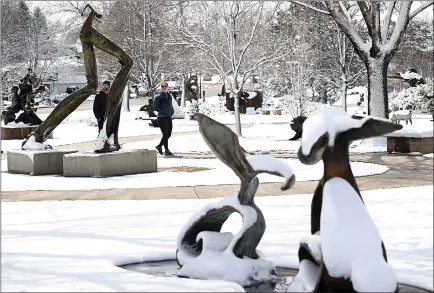  ?? JENNY SPARKS — LOVELAND REPORTER-HERALD ?? Caleb Anderson, left, and Audrey Killoran, center, walk through a snowy Benson Sculpture Park Monday in Loveland. The National Weather Service says mostly sunny conditions will return to Loveland for the rest of the week.