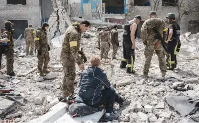  ?? Picture: AFP ?? DEATH WATCH. Yarvoslava, 51, who believes her husband is under the debris, waits as soldiers and members of a rescue team clear the scene after an abandoned school was shelled in Sydorove, Ukraine.