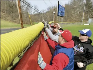  ?? RECORD FILE PHOTOS ?? Spring Little League members Sean Tuckey, Pat McBride and Dan Mahar hang windscreen­s on the outfield fence at the league’s field in Troy during the Tri-City ValleyCats’ 4in 24youth field renovation­s day April 18, 2014.