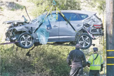  ?? RINGO H.W. CHIU/ASSOCIATED PRESS FILE PHOTO ?? A crane lifts a vehicle Feb. 23 following a rollover accident involving golfer Tiger Woods in the Rancho Palos Verdes suburb of Los Angeles. Authoritie­s said Wednesday that Woods was speeding when he crashed, which left him seriously injured.