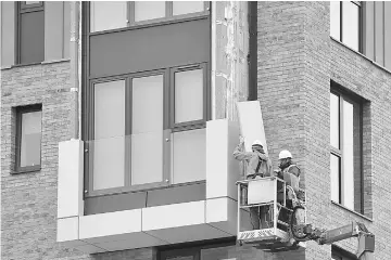  ??  ?? Workers remove panels of external cladding from the facade of a building in the Wythenshaw­e area of Manchester, northwest England. — AFP photo