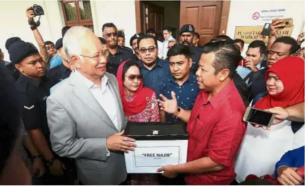  ??  ?? Grateful for contributi­on: Najib together with Rosmah receiving the money from the ‘FreeNajib’ fund from FT Youth Chief Datuk Razlan Rafli at the Kuala Lumpur High Court.