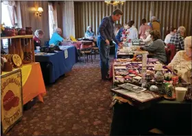  ?? ?? Les Noll, one of the Zammelaaf organizers, examines an item among the vendor displays at the PA German Zammelaaf event held at the Midway Diner in Bethel on March 18.