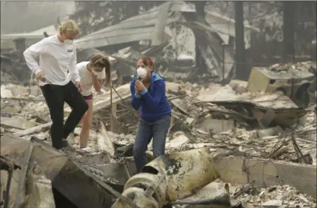  ?? JEFF CHIU — THE ASSOCIATED PRESS ?? Mary Caughey, center in blue, reacts with her son Harrison, left, after finding her wedding ring in debris at her home destroyed by fires in Kenwood Tuesday.