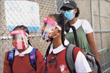  ?? John Minchillo / Associated Press ?? In this Sept. 9 file photo, students wear protective masks as they arrive for classes at the Immaculate Conception School while observing COVID-19 prevention protocols in the Bronx. New York City has again delayed the planned start of in-person learning for most of the more than 1 million students in its public school system.