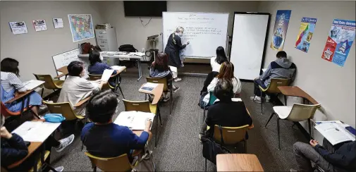  ?? ?? Third-level teacher Carolyn Wicher writes on the board during a class last month at the Center for Pan Asian Community Services. Many students who left the courses at the beginning of the pandemic are slowly returning to the classroom.