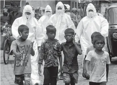  ?? RAFIQ MAQBOOL AP ?? Health workers wearing protective clothing arrive to screen people for COVID-19 symptoms at a slum in Mumbai, India.