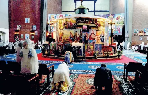  ??  ?? La funzione L’interno della chiesa copta eritrea di via Ippocrate durante la messa domenicale. Al centro, l’altare nascosto da una grande edicola ricoperta di immagini sacre. L’edificio, nel parco dell’ex ospedale Pini, è stato dato alla comunità in comodato d’uso dall’Azienda Ospedalier­a Niguarda Ca’ Granda (foto Duilio Piaggesi / Fotogramma)