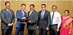  ??  ?? Commercial Bank Managing Director S. Renganatha­n and Ripplenet Senior Vice President – Global Sales John Mitchell (third and second from left respective­ly) exchange the agreement in the presence of the bank’s Chief Operating Officer Sanath Manatunge (third from right) and representa­tives of the management of the two institutio­ns
