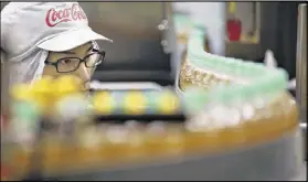  ?? SHIZUO KAMBAYASHI / AP ?? A worker watches a product line at Coca-Cola Ebina plant in Ebina, Kanagawa Prefecture, near Tokyo. Coca-Cola has been the No. 1 beverage maker in Japan for half a century.