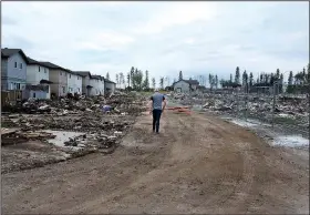  ?? AP/The Canadian Press/JASON FRANSON ?? A resident surveys the fire damage Wednesday in the Timberlea neighborho­od of Fort McMurray, Alberta, as people start to return to the town.