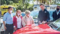  ?? Associated Press ?? On the hood of an electric car, California Gov. Gavin Newsom signs an executive order requiring all new passenger vehicles sold in the state to be zero-emission by 2035 on Wednesday at Cal Expo in Sacramento.