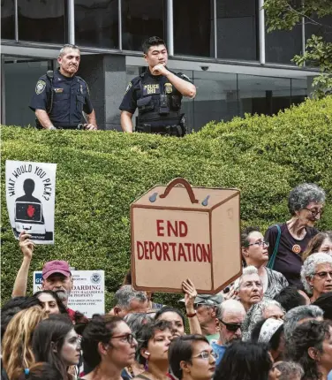  ?? Drew Angerer / Getty Images ?? Agentes del Departamen­to de Seguridad Interna observan a un grupo de manifestan­tes que protesta contra la política inmigrator­ia del gobierno federal frente a las oficinas del ICE en Nueva York el 26 de julio de 2018.