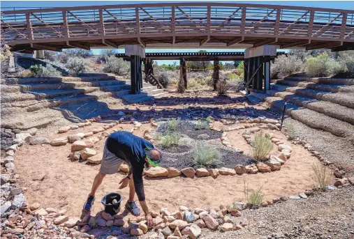  ?? EDDIE MOORE/JOURNAL ?? Artist and author John Thompson moves rocks into place as he builds a labyrinth in the Arroyo Chamisa in Santa Fe on May 25. He said he found the process of building a labyrinth much like that of writing a book: editing, revising and drafting.