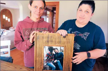  ?? (AP/The Hickory Daily Record/Robert C. Reed) ?? Jessica Lail (left) holds a photo of Jason Lail with her sister-in-law, Kristen Lail, on Sept. 13 in Conover, N.C. Jason Lail died from complicati­ons from covid-19 despite being health and having no medical conditions.