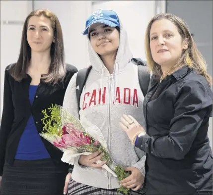  ?? Chris Young / The Canadian Press via Associated Press ?? Rahaf Mohammed Alqunun, 18, center, stands with Canadian Minister of Foreign Affairs Chrystia Freeland, right, as she arrives at Toronto Pearson Internatio­nal Airport, on Saturday. The Saudi teen fled her family while visiting Kuwait and flew to Bangkok, where she barricaded herself in an airport hotel and launched a Twitter campaign.