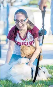  ?? JENNIFER LETT/STAFF PHOTOGRAPH­ER ?? Alexandra Geisser, a sophomore at Stoneman Douglas pets Milly, a therapy dog. Milly was “the only thing that made me smile all day,” she said.