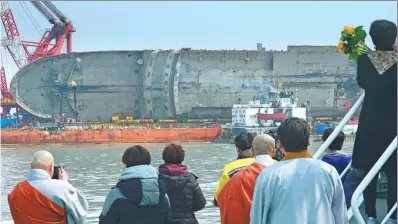  ?? YONHAP VIA ASSOCIATED PRESS ?? Relatives of the missing victims attend a memorial ceremony near the sunken ferry waters off Jindo, South Korea, on Tuesday. on a semi-submersibl­e transport vessel in