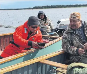  ?? THE CANADIAN PRESS ?? Lawrence Kanatewat, right, Merlin Kanatewat, in back, watch researcher Dante Torio as he takes a water sample from James Bay near Wemindji, Que.