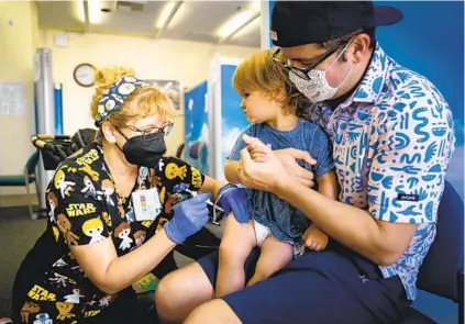  ?? NELVIN C. CEPEDA U-T ?? Ryan Balke of South Park holds 23-month-old Pippa still so she can receive a Moderna vaccine from registered nurse Shelley Abcarius on Tuesday at Rady Children’s Hospital. It was the first day children younger than 5 were eligible for vaccinatio­n.