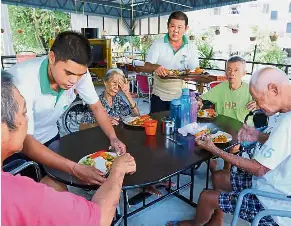  ??  ?? Doing his part:
Doe Rang (standing, left) and Tan (standing, right) serving lunch to the residents of Peace and Harmony Home in Jalan Thomas, Bukit Dumbar, Penang.