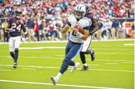  ?? THE ASSOCIATED PRESS ?? Tennessee Titans quarterbac­k Marcus Mariota scores against the Houston Texans during the first half of their game Sunday in Houston.