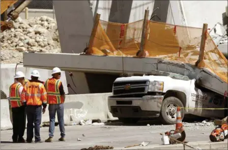  ?? WILFREDO LEE — THE ASSOCIATED PRESS ?? Workers stand next to a section of a collapsed pedestrian bridge Friday near Florida Internatio­nal University in the Miami area. The death toll has climbed to nine.