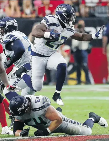  ?? RICK SCUTERI/THE ASSOCIATED PRESS ?? Seahawks running back Mike Davis leaps over a teammate Sunday on his way to 101 yards rushing against the Arizona Cardinals. The 20-17 win was Seattle’s second consecutiv­e victory.