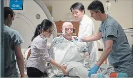  ??  ?? Sky Zazlov is helped up by members of the medical team after she completes her treatment in a MRI machine following a focused ultrasound procedure, at Toronto's Sunnybrook Hospital.