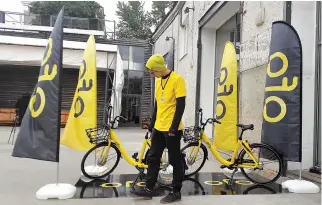  ??  ?? A PARTICIPAN­T stands next to bicycles during a presentati­on, organized by bike-sharing start-up Ofo, in Moscow, Russia, Sept. 22.