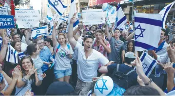  ??  ?? PRO-ISRAEL SUPPORTERS dance during a rally in New York’s Times Square in 2014.