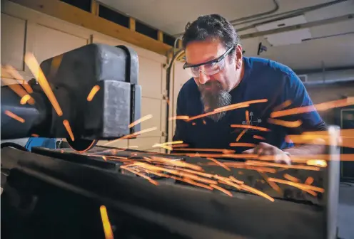  ?? GABRIELA CAMPOS/THE NEW MEXICAN ?? Sparks fly around Rick Kennedy, a Santa Fe County gunsmith, while he shapes a specialize­d tool on a grinder at his Edgewood workshop. Kennedy was chosen as one of 24 craftsmen and craftswome­n from across the country to compete in Discovery Channel’s Master of Arms.