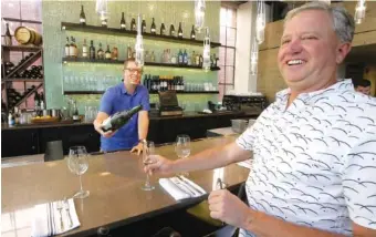  ?? THE ASSOCIATED PRESS ?? Andrew Cliburn, left, pours a glass of champagne for Joel LaSalle, Current Fish and Oyster owner, after a partition known as the “Zion Curtain” that prevented customers from seeing their alcoholic drinks being mixed and poured, was taken down in Salt...