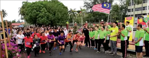  ??  ?? Ling (holding the Malaysian flag), accompanie­d by Ong and PTA chairman Dr Aziz Abdul Rahim, flags off the jogathon.