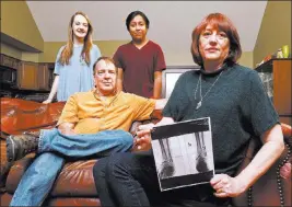  ?? WADE PAYNE/ THE ASSOCIATED PRESS ?? Leslie Kurtz, right, sits with her husband, Bart Bartram, daughter Rainey, and son Rio as she holds an X-ray of her ankle Sunday in Knoxville, Tenn. Her county is one of 16 in Tennessee that lack even a single insurance company committed to offering...