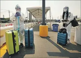  ?? Al Seib Los Angeles Times ?? TWO FRIENDS wait for a Lyft driver at LAX last week. The Centers for Disease Control and Prevention no longer recommends a 14-day quarantine for travelers.