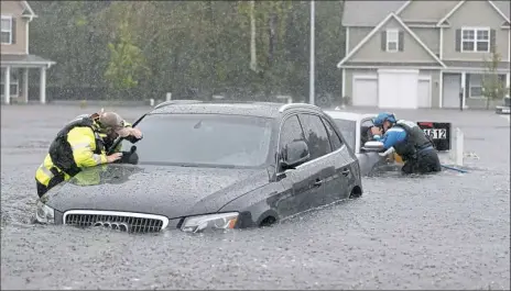  ?? David Goldman/Associated Press ?? Members of the North Carolina Task Force urban search and rescue team check cars in a flooded neighborho­od looking for residents who stayed behind as Florence continues to dump heavy rain in Fayettevil­le, N.C., on Sunday.