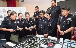  ??  ?? Fool tools: Comm Mazlan (left) looking at one of the seized mobile phones during the press conference at the state police headquarte­rs in Shah Alam.