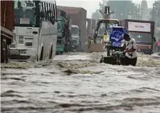  ?? AFP ?? A man pulls his cart through floodwater­s in Hero Honda chowk during a downpour in Gurgaon yesterday.