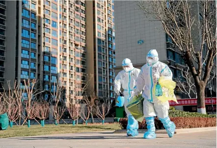  ?? AP ?? Health workers carry a container of coronaviru­s test samples taken from residents at a housing complex in Shijiazhua­ng in northern China’s Hebei province. Millions of people are being tested as part of efforts to control China’s most serious recent outbreak of Covid-19.