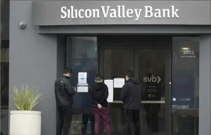  ?? Jeff Chiu/Associated Press ?? People look at signs posted outside of an entrance to Silicon Valley Bank in Santa Clara, Calif., March 10.
