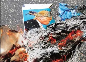  ?? ABBAS MOMANI/AFP ?? The remains of a burnt flyer, depicting US President Donald Trump defaced with cartoon shoes on his head, during a protest against the arrival of the US delegation, in the West Bank city of Ramallah yesterday.