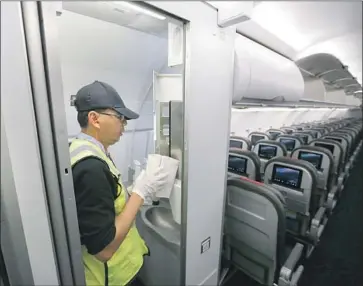  ?? Allen J. Schaben Los Angeles Times ?? THE NEW RESTROOMS are sparking complaints from pilots, concerns from f light attendants and griping from travelers. Above, a worker adds paper towels to the lavatory on an American Airlines jet at LAX in 2016.