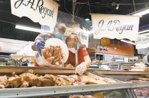  ?? LLOYD FOX/BALTIMORE SUN ?? Tony Hutchins and Grace Cho stock pig tails and sauerkraut, some of the big sellers around Thanksgivi­ng, on Monday at J.A. Regan at the Lexington Market.