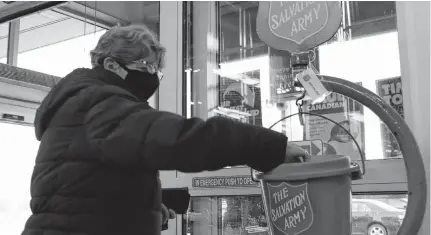  ??  ?? A woman puts a donation into a Salvation Army kettle at a grocery store in Spryfield on Thursday.