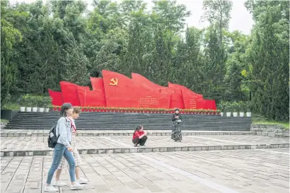  ??  ?? ABOVE RIGHT Students walk past a patriotic monument at Chongqing Capital Normal University in Chongqing, China.