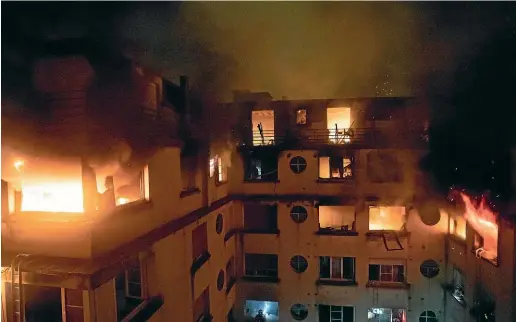  ?? AP ?? A fire rages through the top floors of an apartment building in Paris, France. The fire that authoritie­s suspect was an arson attack sent residents fleeing to the roof or climbing out their windows to escape.