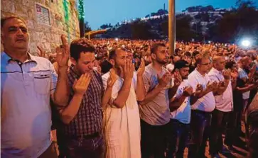  ??  ?? PENDUDUK Palestin berdoa selepas bersolat di hadapan pintu masuk Al-Aqsa malam kelmarin. - AFP