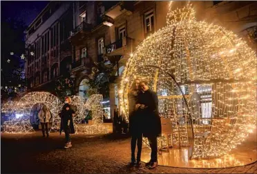  ?? Louisa Gouliamaki AFP/ Getty I mages ?? I N ATHENS, Greeks gather near illuminate­d displays welcoming 2021. Around the world, the New Year’s experience mirrored national responses to the COVID- 19 pandemic. Some countries canceled or scaled back festivitie­s, while others carried on as in past years. In Mandalay, right, people cross the Irrawaddy River during the last sunset of the year in Myanmar.